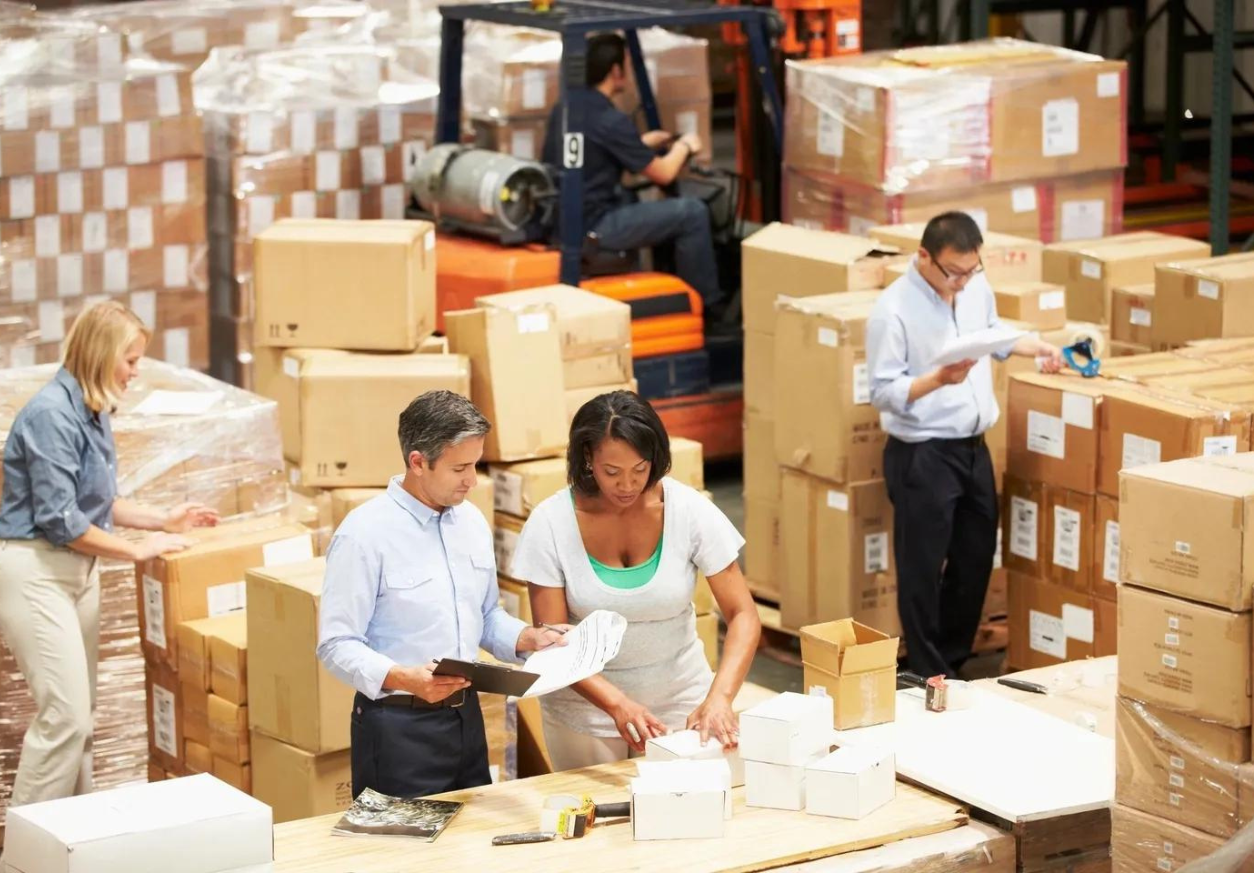 A group of people in warehouse with boxes.